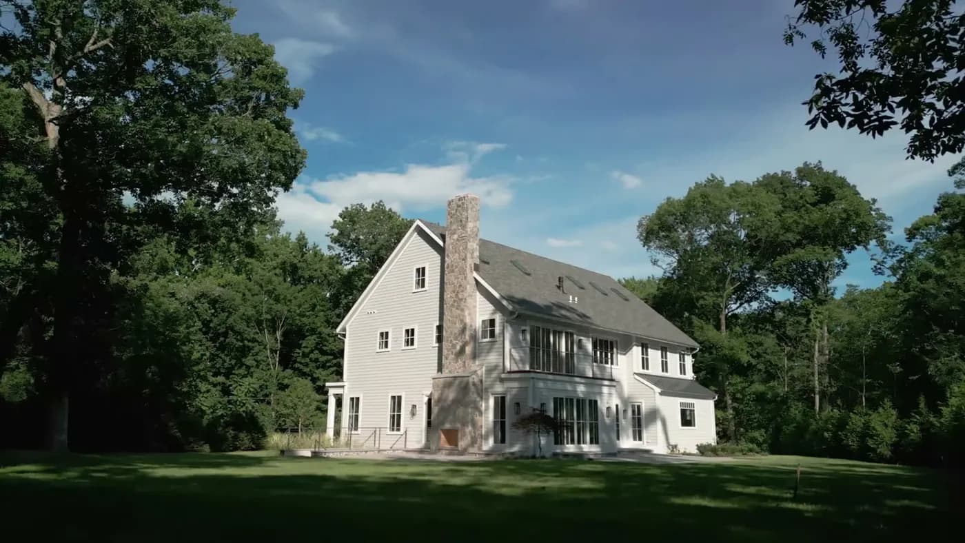 Brick masonry chimney above a shingled roof with weathered mortar joints and a concrete crown