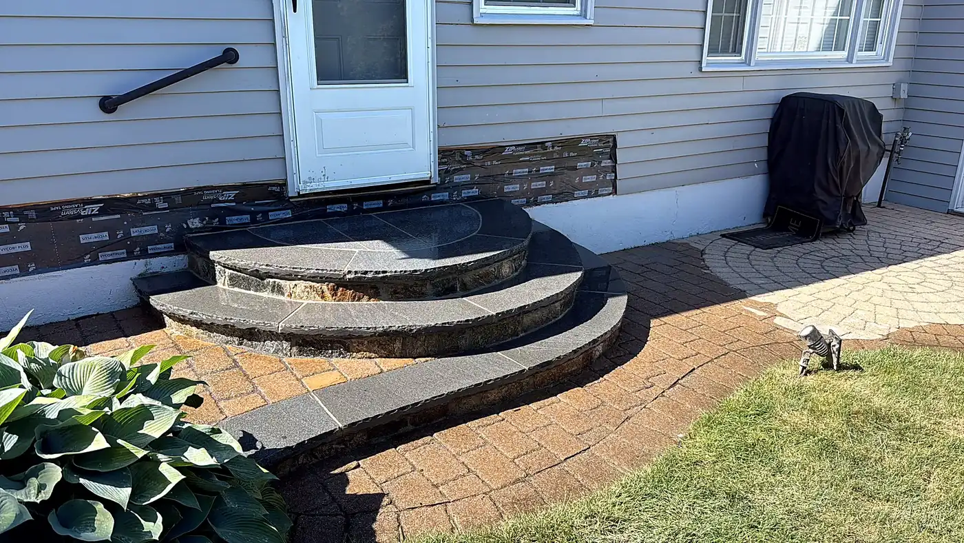 Fieldstone wall running along the edge of a lawn in a New England yard with stones stacked tightly without visible mortar