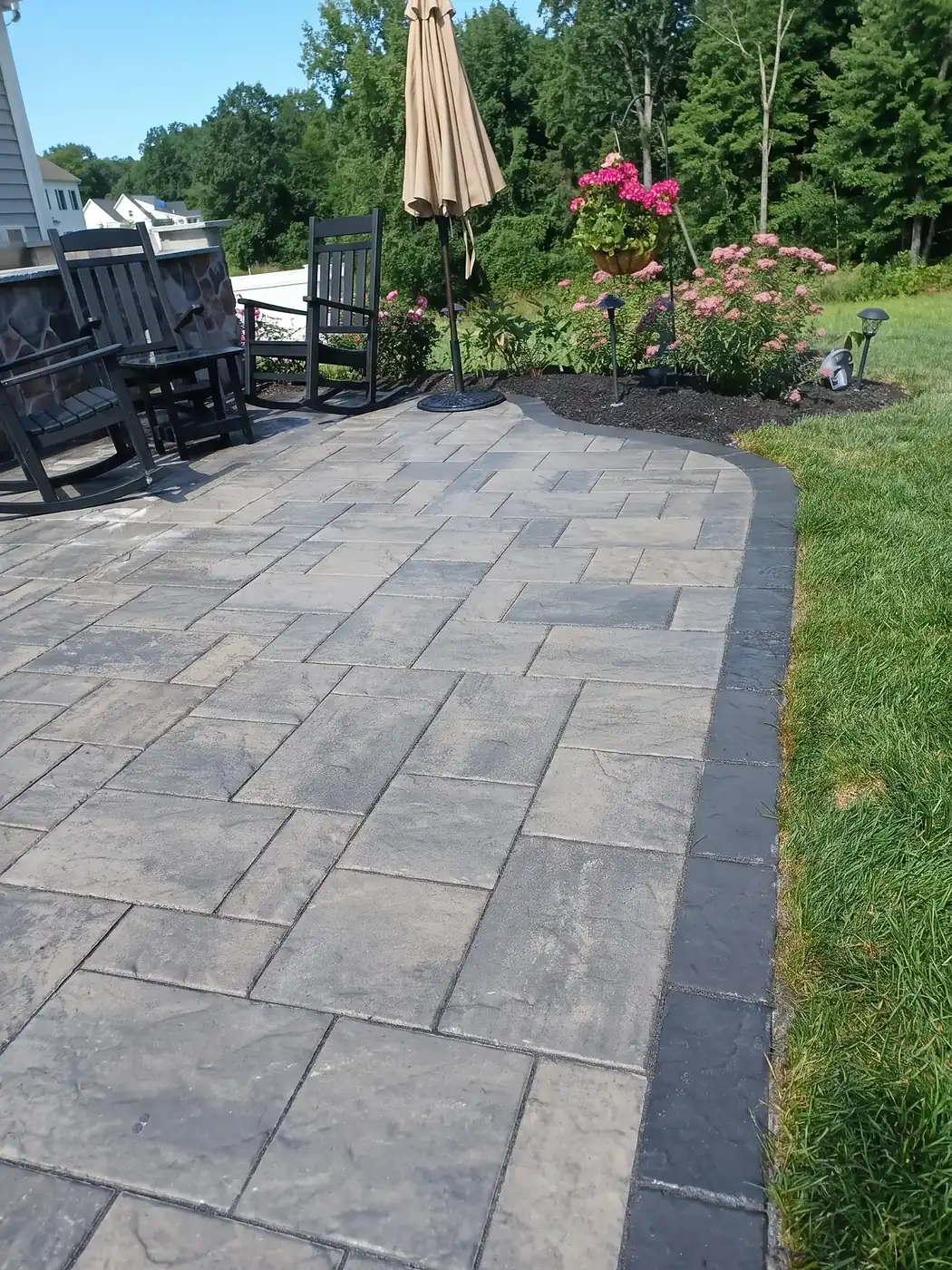 Paver walkway with a planted border leading to the front door of a suburban New England home