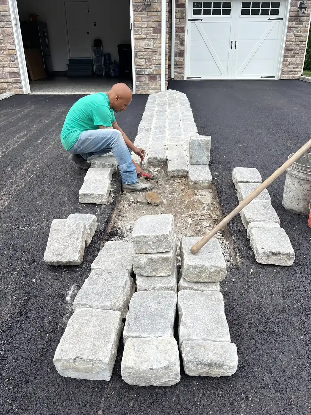 Granite cobblestone apron edging an asphalt driveway at the entrance to a home garage