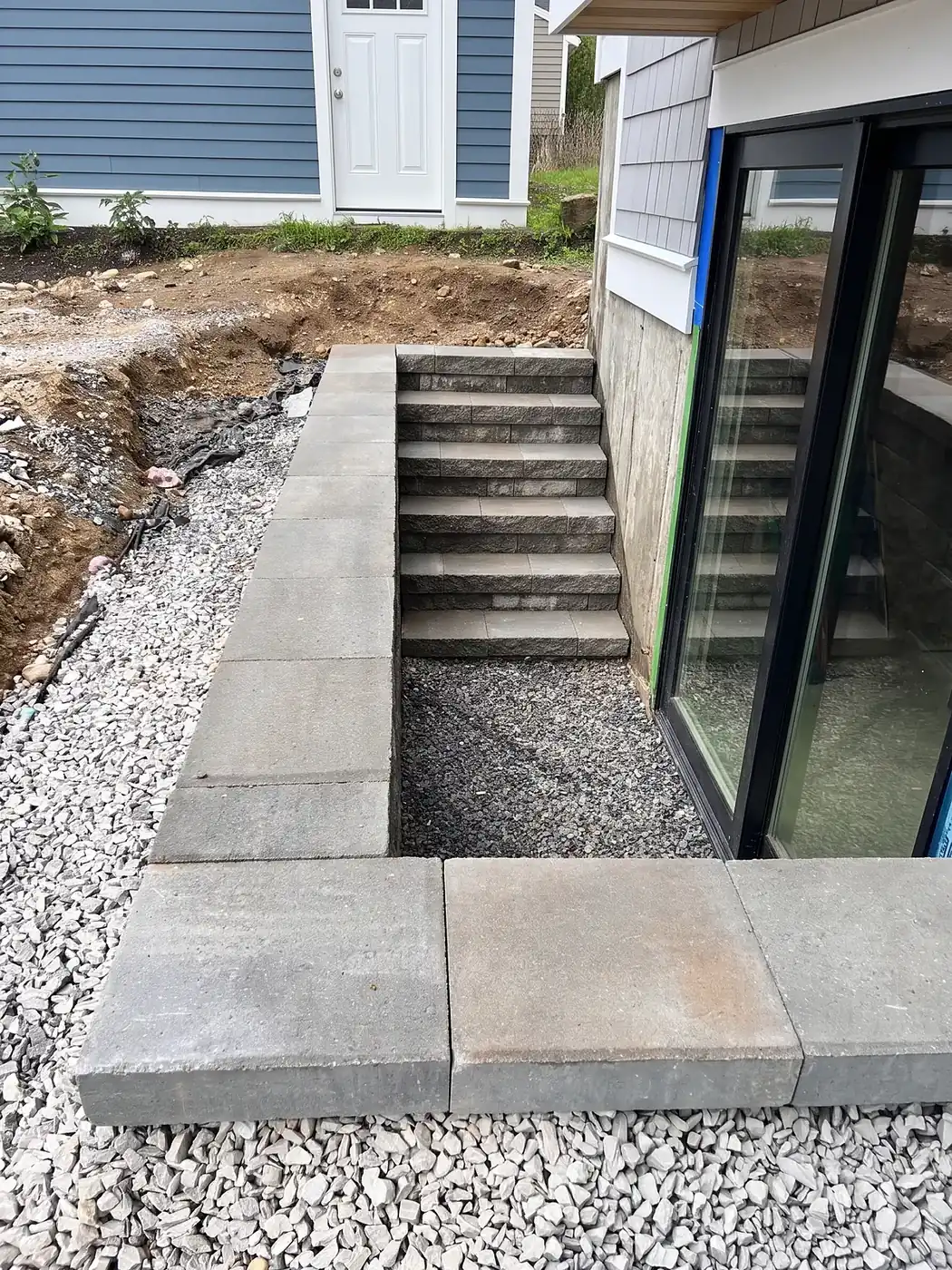 Curved segmental block retaining wall holding back a sloped backyard with a level lawn above