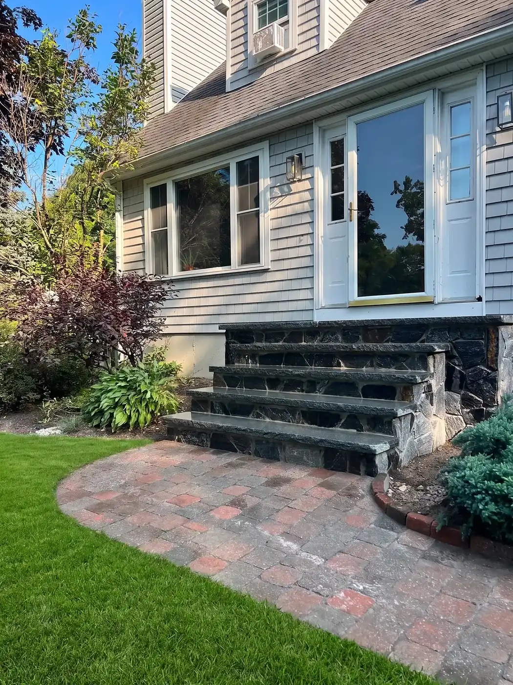 Fieldstone veneer wall at the entry of a home with a paver walkway leading to the front steps