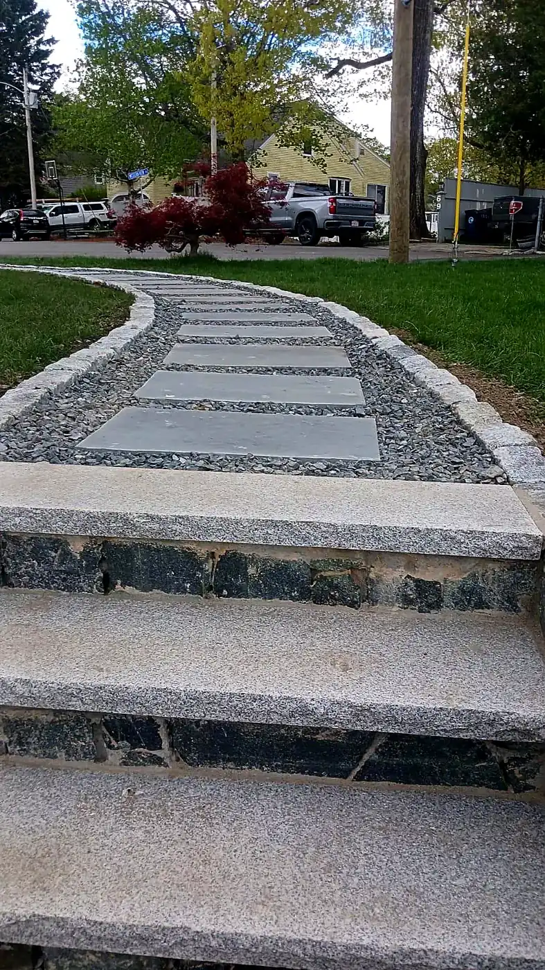 Bluestone slab walkway with pea stone joints and a granite cobblestone border leading to a front entry