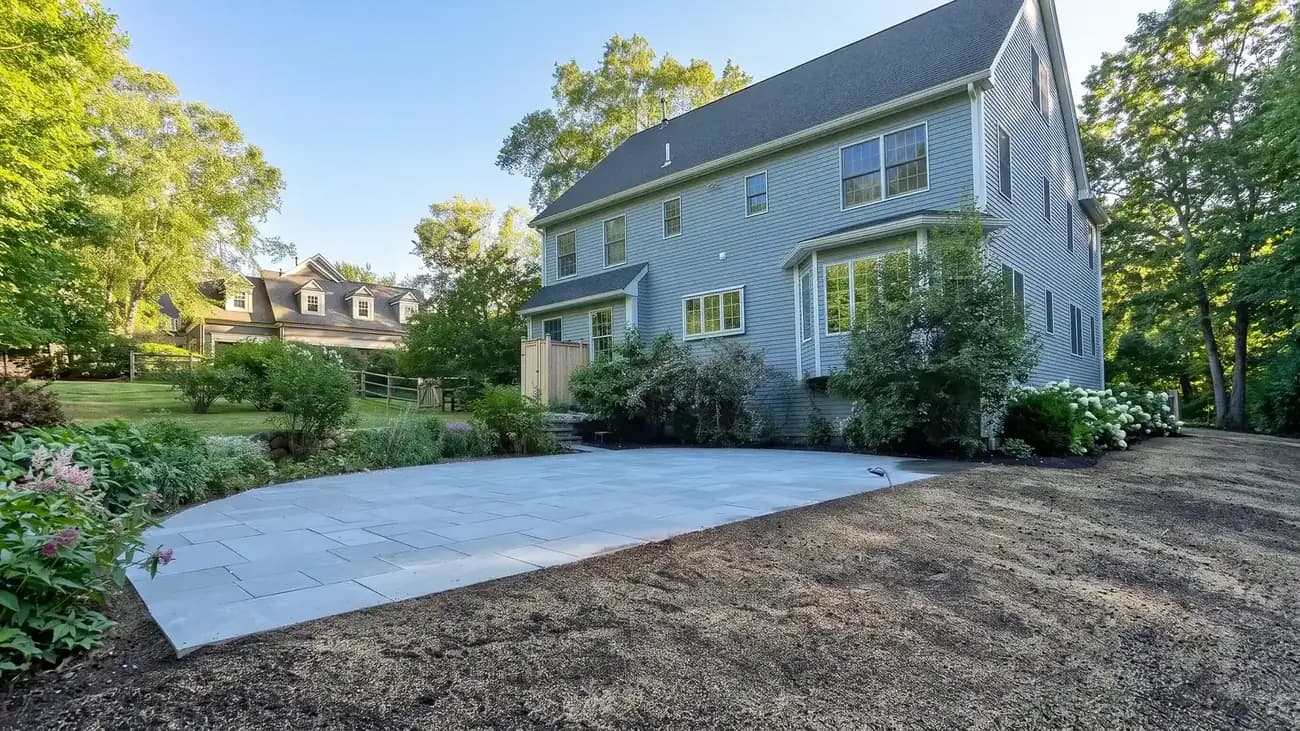 New bluestone patio with a curved edge behind a two-story colonial home
